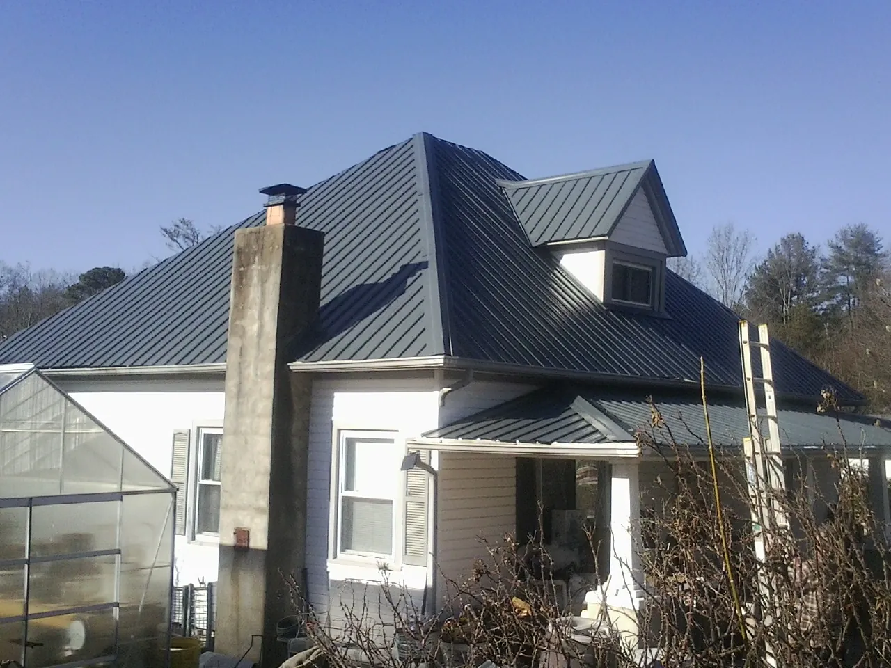 Dark blue standing seam metal roof on a white farmhouse with dormer — Slate & Tile Roof Repair by Roofing Brothers in Umatilla