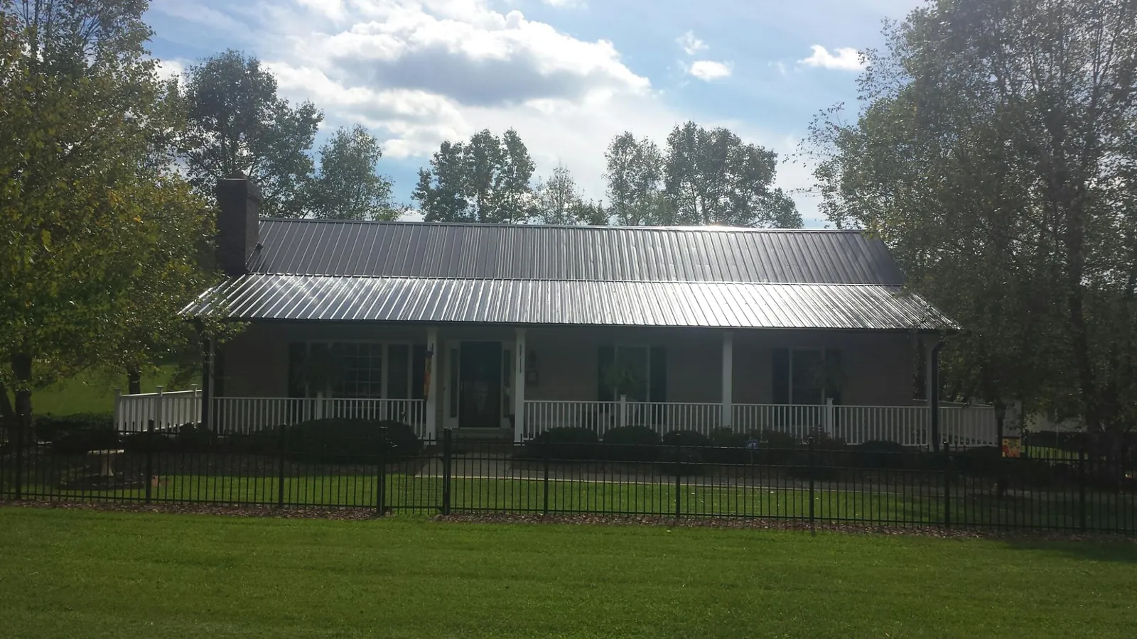 Gray metal roof on a brick ranch with a full width front porch — Gutter Guard Installation work by our crew in Umatilla