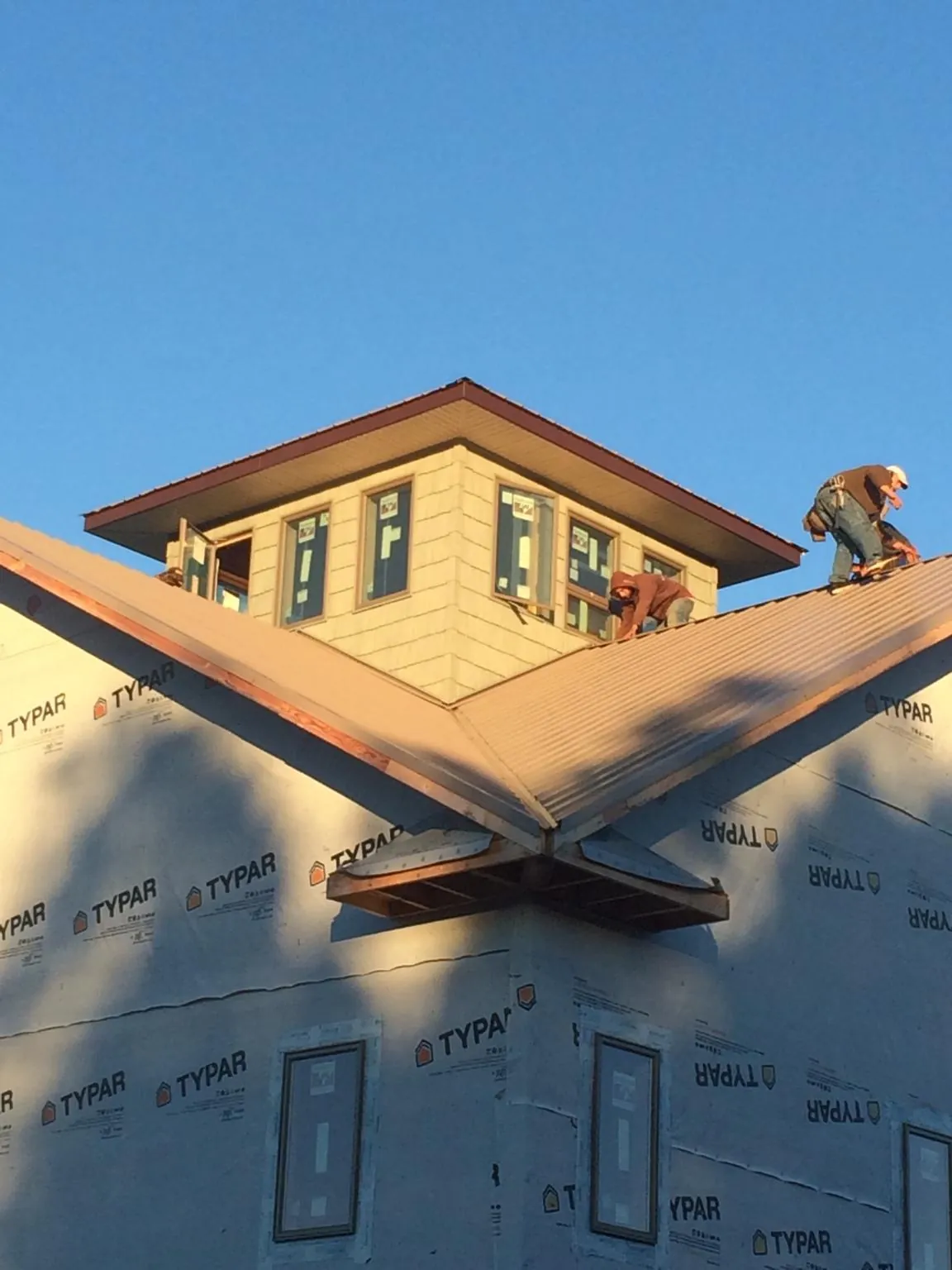 Roofers working around a rooftop cupola on a new metal roof at sunset — Roof Waterproofing in Umatilla by Roofing Brothers